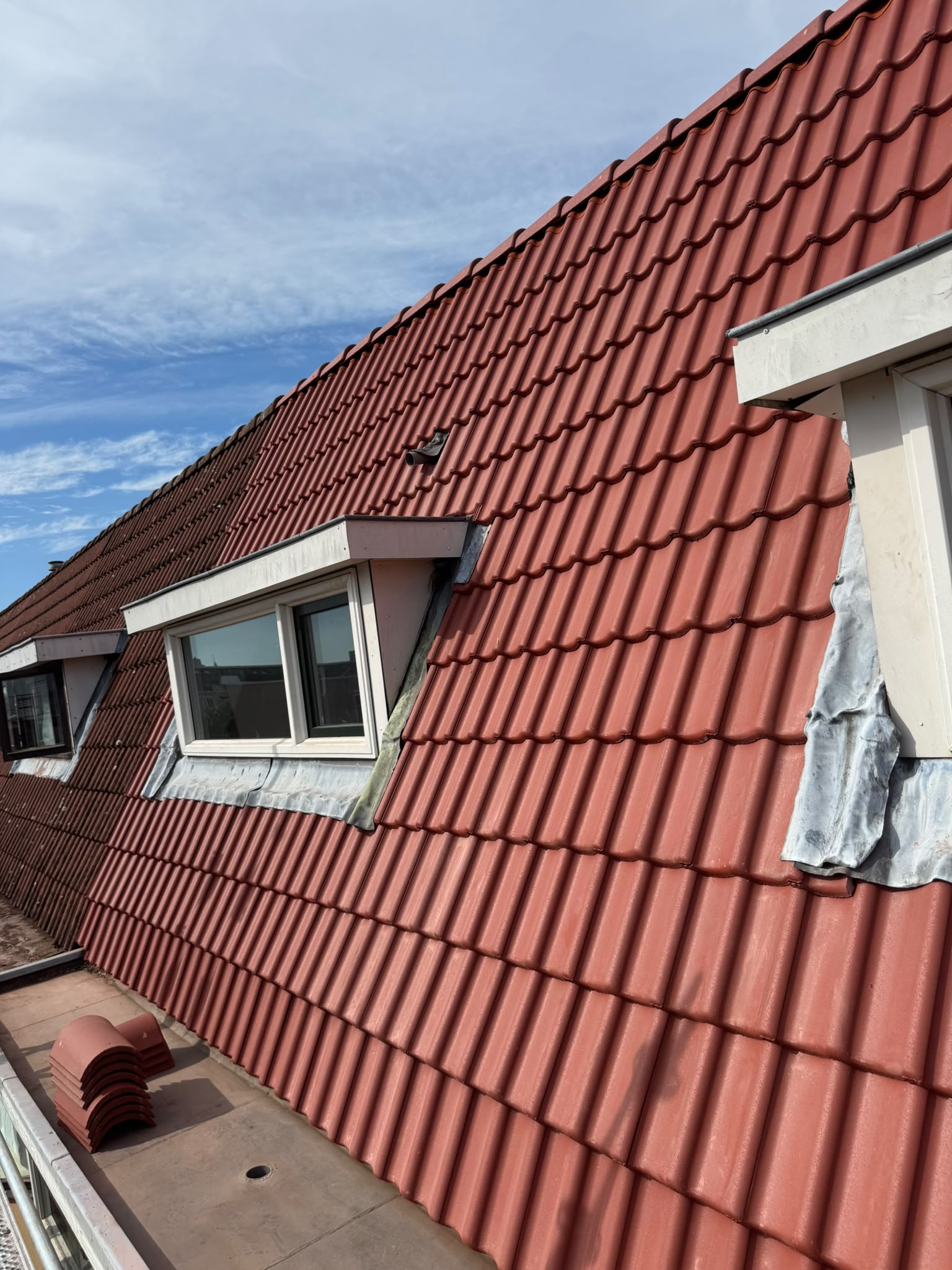 Dakrenovatie Haarlem lange dakzijde met rode dakpannen